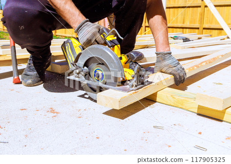 Cutting of wood beams is performed with an electrically powered circular saw 117905325