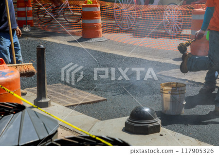 Repairs are being made to damaged part of road that is being rebuilt by worker 117905326
