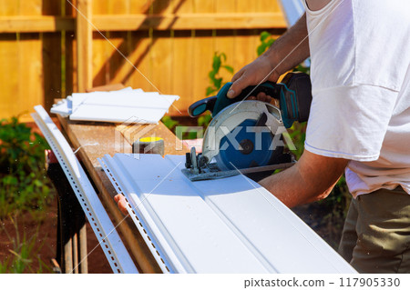 Prior to installing vinyl siding panels on craftsman facade, vinyl siding panels are cut to desired sizes during construction 117905330