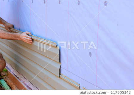 An installation process for vinyl PVC siding on new home facade by handyman 117905342