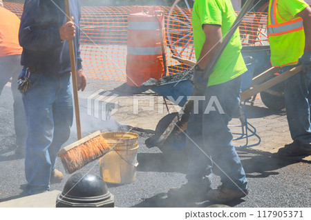 Worker is engaged in repairing damaged part of reconstruction road 117905371