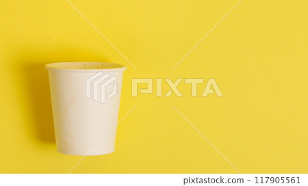 Disposable paper cup for coffee and tea on a bright orange background. Disposable paper cup for coffee and tea on a bright orange background. 117905561