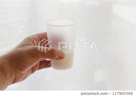 Hand holding a glass of liquid. Hand holding a glass of liquid. 117905568