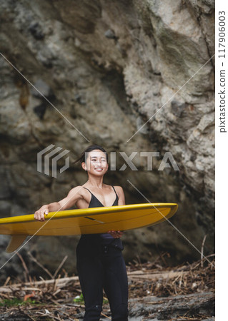 在岩石地區拿著衝浪板的年輕女子 117906003