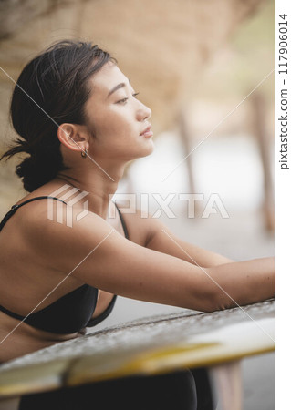 在岩石地區拿著衝浪板的年輕女子 117906014