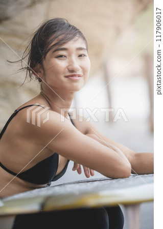 Young woman holding a surfboard on the rocks Young woman holding a surfboard on the rocks 117906017
