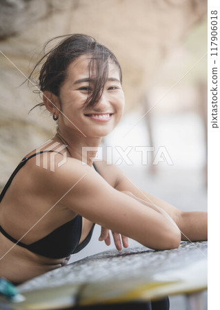 在岩石地區拿著衝浪板的年輕女子 117906018