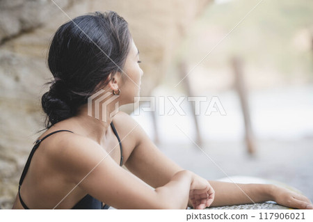 Young woman holding a surfboard on the rocks Young woman holding a surfboard on the rocks 117906021