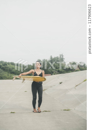 拿著衝浪板沿著海灘散步的年輕女子 117906623