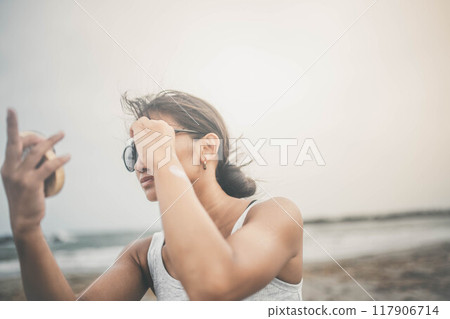 Young woman doing skin care at the beach 117906714