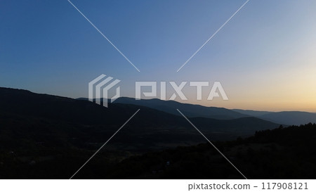 A tranquil twilight over rolling hills creates a serene landscape in the fading light of sunset A tranquil twilight over rolling hills creates a serene landscape in the fading light of sunset 117908121