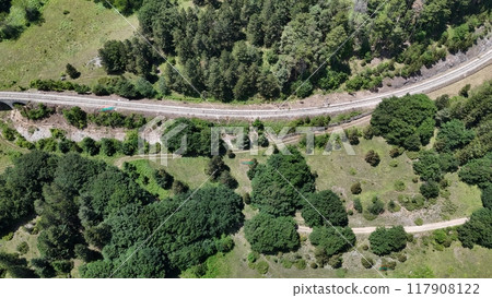 Aerial view of a winding railway nestled among vibrant green forests in the serene countryside during a sunny afternoon Aerial view of a winding railway nestled among vibrant green forests in the serene countryside during a sunny afternoon 117908122