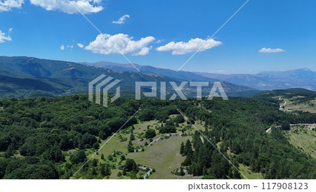 Breathtaking view of lush green valleys and distant mountains under a blue sky with fluffy clouds Breathtaking view of lush green valleys and distant mountains under a blue sky with fluffy clouds 117908123