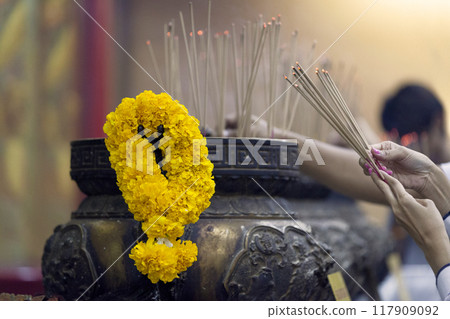 Burning incense sticks and offering garland of flowers 117909092