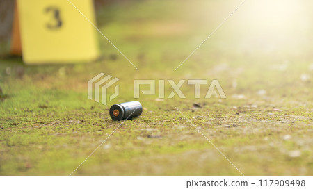Spent bullet casing lying on the ground with blur number 3 sign. Concepts of shooting sports and security highlighting the dual nature of firearms in both competitive sport and protective measures. Spent bullet casing lying on the ground with blur number 3 sign. Concepts of shooting sports and security highlighting the dual nature of firearms in both competitive sport and protective measures. 117909498