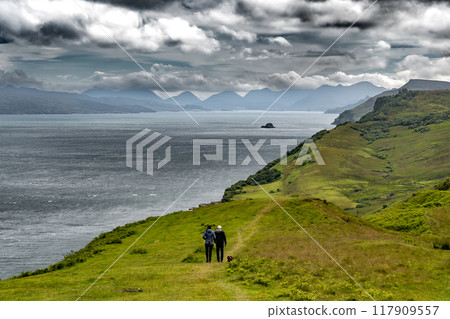 Couple With Dog Walks Along The Atlantic Coast On The Isle Of Skye In Scotland, UK Couple With Dog Walks Along The Atlantic Coast On The Isle Of Skye In Scotland, UK 117909557