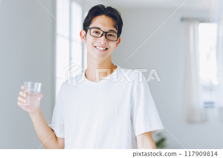 年輕人從玻璃杯裡喝水 117909814