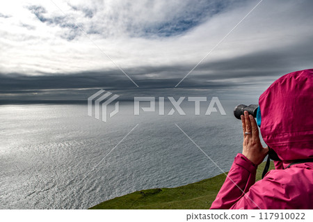 Woman With Spyglass Looks Over The Atlantic Ocean At The Cliffs Of The Isle Of Skye In Scotland, UK Woman With Spyglass Looks Over The Atlantic Ocean At The Cliffs Of The Isle Of Skye In Scotland, UK 117910022