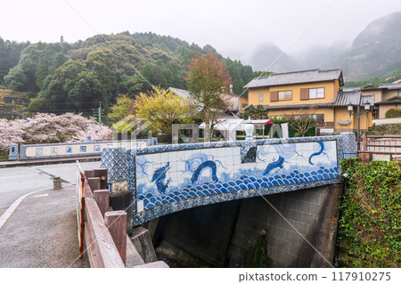 Okawachiyama bridge entrance to village with cherry tree, imari Okawachiyama bridge entrance to village with cherry tree, imari 117910275