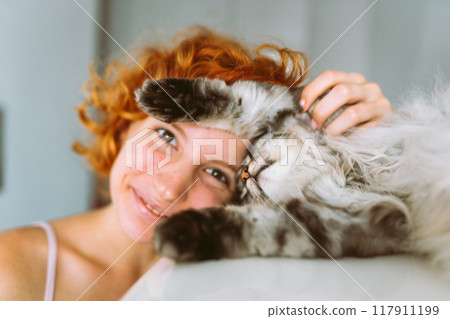 portrait red-haired teenage girl with gray fluffy cat 117911199