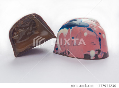 Tempered chocolate candies with a glossy painted body and fruit filling with blur elements 117911230