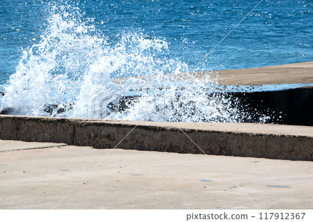 Powerful dynamic waves continuously crash against the pier 117912367