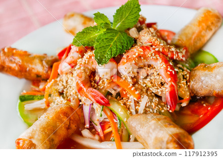 Traditional asian cuisine - fried spring rolls with shrimps, fresh vegetables, sesame and mint leaves. Vietnamese food at cafe. 117912395
