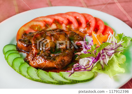 Traditional asian cuisine - fried pork in sweet and sour sauce, fresh vegetables, sesame and mint leaves. Vietnamese food at cafe. Traditional asian cuisine - fried pork in sweet and sour sauce, fresh vegetables, sesame and mint leaves. Vietnamese food at cafe. 117912396