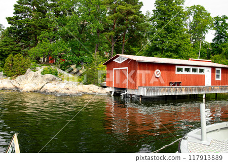 traditional red wooden fisherman's house with white door and windows on the Swedish archipelago at the water's edge 117913889