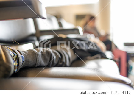 Selective focus on the feet of a child asleep on a row of chairs in an airplane terminal  117914112