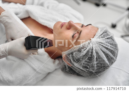 Woman receiving skin treatment at a spa in a bright, clean environment Woman receiving skin treatment at a spa in a bright, clean environment 117914710