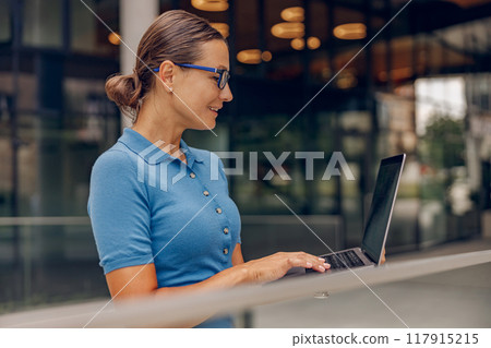 A Professional Woman Concentrating on Her Laptop in a Contemporary Office Environment 117915215