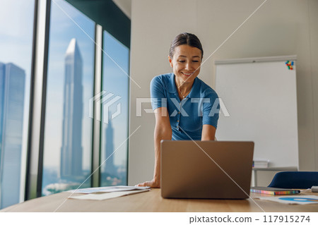 A Professional Woman Engaged in Her Work at a Laptop Within a Contemporary Office Environment 117915274