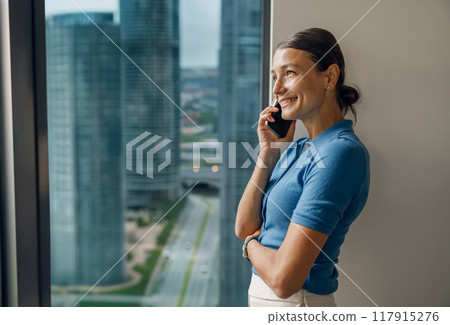A Professional Woman Engaged in a Phone Conversation Inside a Modern Office Environment 117915276