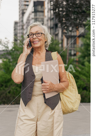 A Cheerful Senior Woman with a Smartphone Enjoys Her Time in an Urban City Setting 117915277