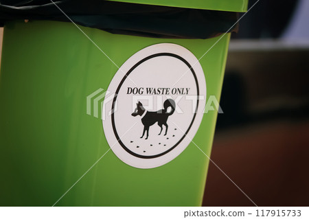 Waste management, green plastic bin featuring a white sign proclaiming its exclusive purpose for dog waste disposal, emphasizing environmental responsibility and the cleanliness of canine excrement. Waste management, green plastic bin featuring a white sign proclaiming its exclusive purpose for dog waste disposal, emphasizing environmental responsibility and the cleanliness of canine excrement. 117915733