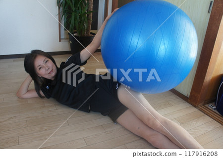 Tall woman riding a balance ball Tall woman riding a balance ball 117916208