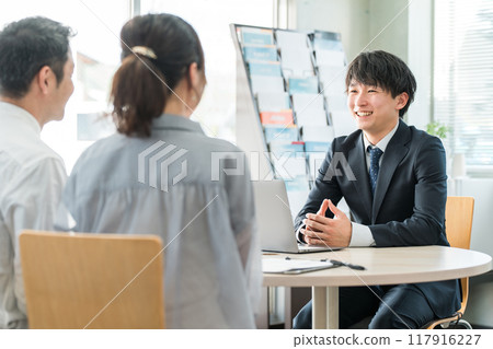 A young Asian businessman and his customer couple serving in a showroom/business negotiation space A young Asian businessman and his customer couple serving in a showroom/business negotiation space 117916227