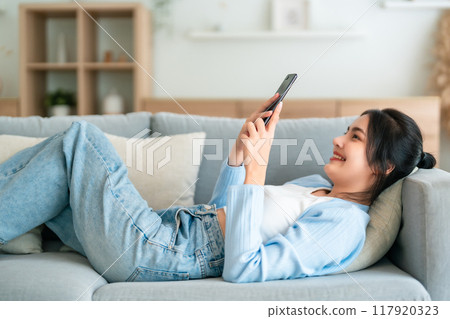 Happy cheerful positive young Asian woman on the phone at home Happy cheerful positive young Asian woman on the phone at home 117920323
