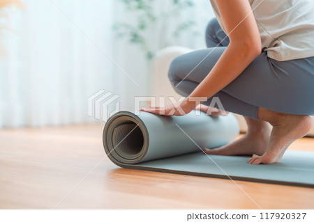 Young Asian woman doing yoga, twisting on a mat in the living room at home 117920327