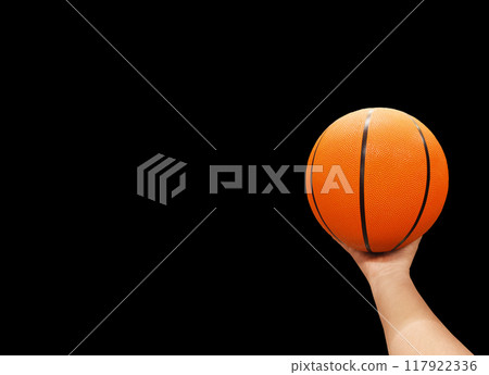 Basketball ball in hand isolated on black background. 117922336