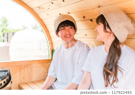 一對穿著 T 恤的年輕夫婦在桑拿浴室裡愉快地交談 一對穿著 T 恤的年輕夫婦在桑拿浴室裡愉快地交談 117922493
