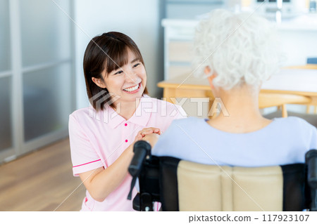 Caregiver supporting a woman in a wheelchair 117923107