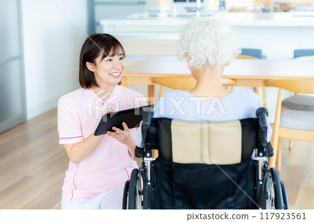 Caregiver supporting a woman in a wheelchair 117923561