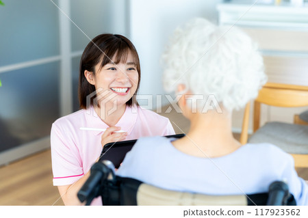 Caregiver supporting a woman in a wheelchair Caregiver supporting a woman in a wheelchair 117923562