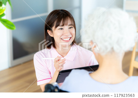 Caregiver supporting a woman in a wheelchair 117923563