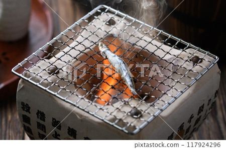 Grilling dried silver-striped round herring 117924296