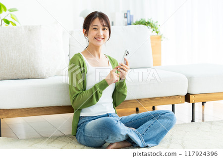 A young woman operating a smartphone in a room A young woman operating a smartphone in a room 117924396