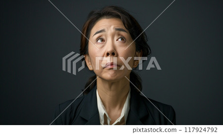 A middle-aged woman in a suit looking up A middle-aged woman in a suit looking up 117924792