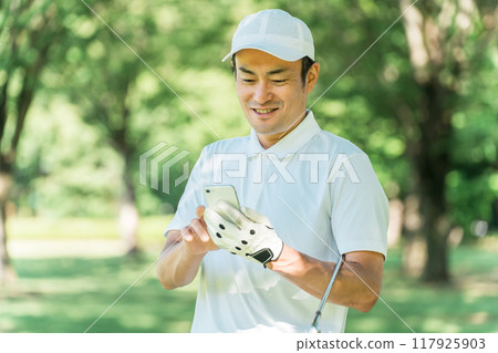 Male golfer using smartphone on golf course (app, score, score management, course strategy, course map) 117925903